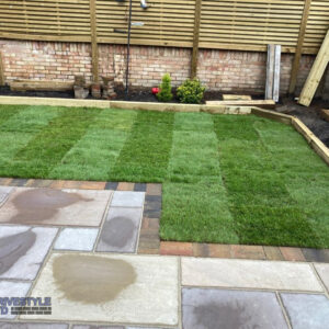 Sandstone Patio with Brick Border, Sleepers and Roll-On Turf in…